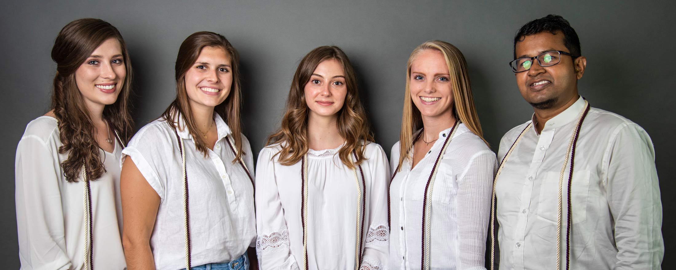 Kappa Omicron Nu officers in white tops on a gray background.