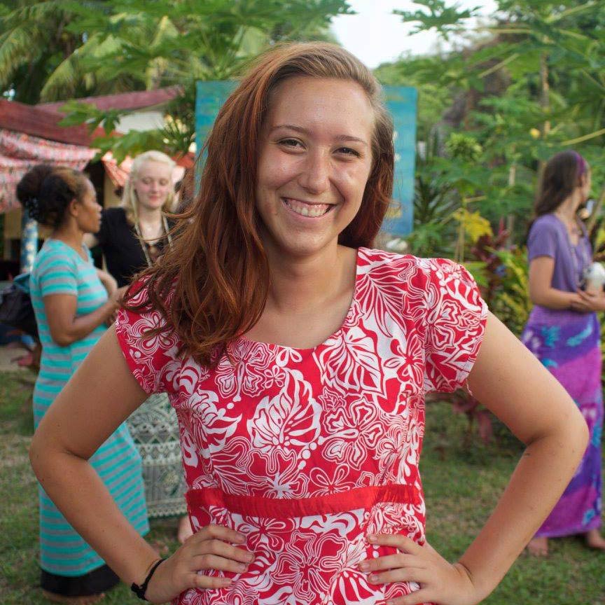 Jenny Boyer smiling with hands on her hips in a red and white flowered dress.