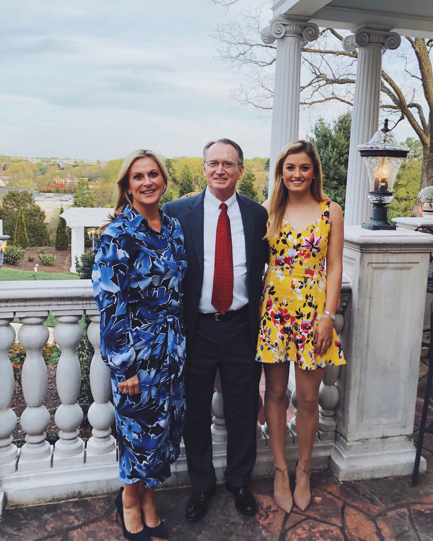 Malan Jackson standing ona balcony in a yellow print dress with her parents.