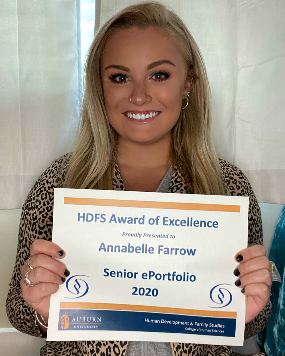 Annabelle holding a plaque of her Senior ePortfolio award.