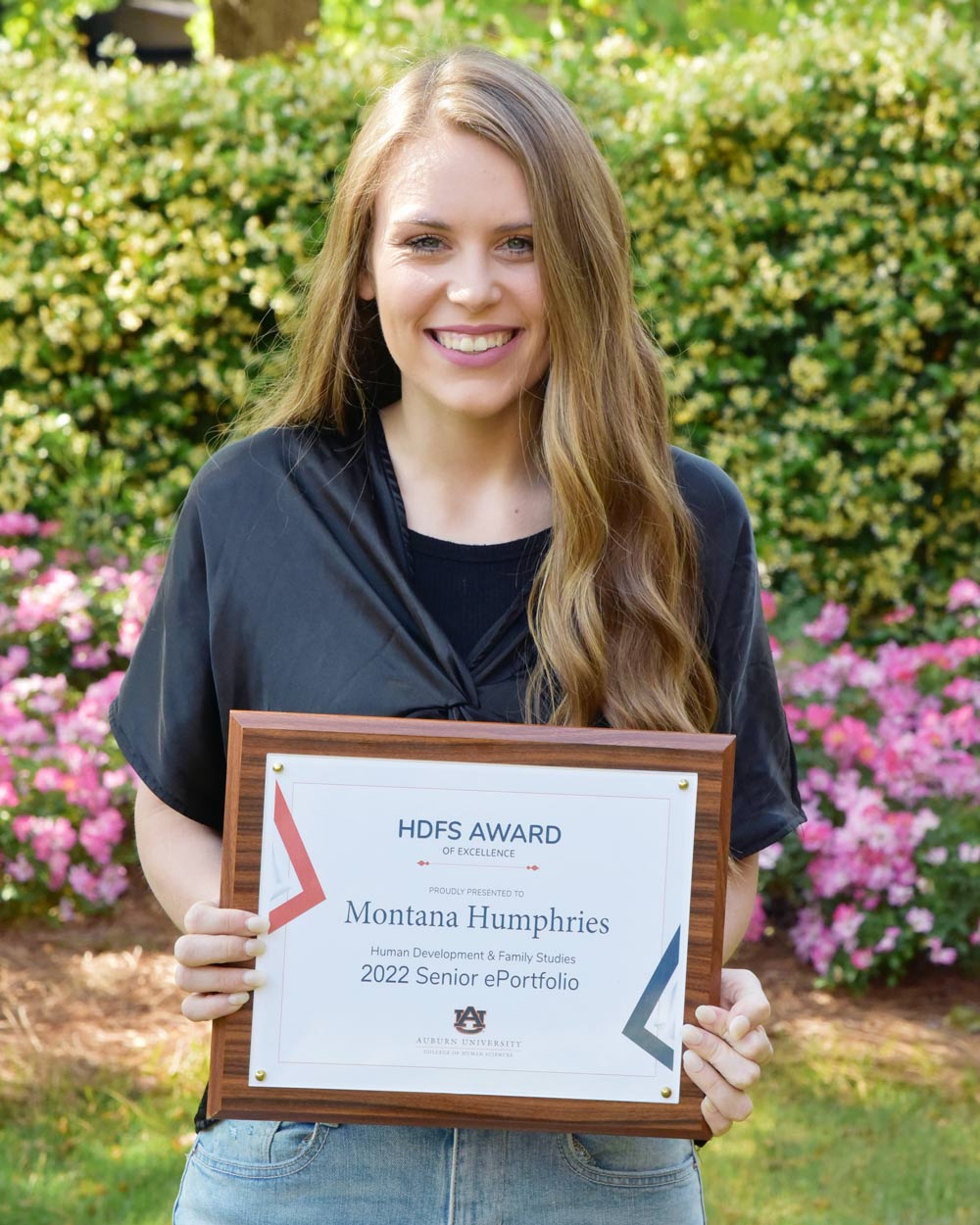 Montana holding a plaque of her Senior ePortfolio award.