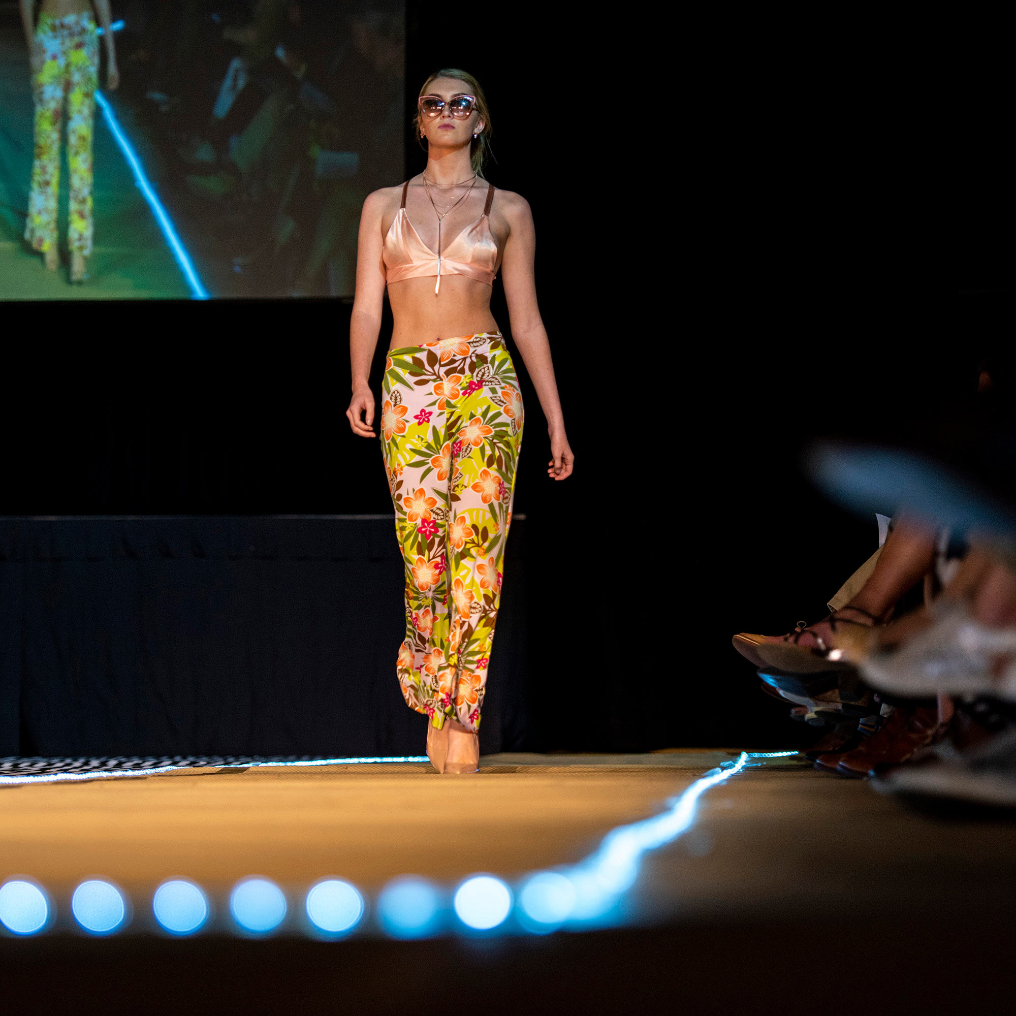 Model walking the runway in floral print pants during The Fashion Event: Mod.