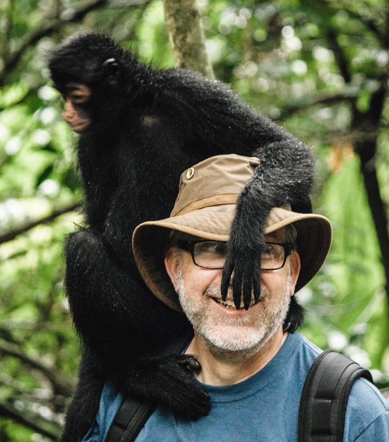 Kyle Hostelecjy with a gibbon monkey resting on his shoulder.