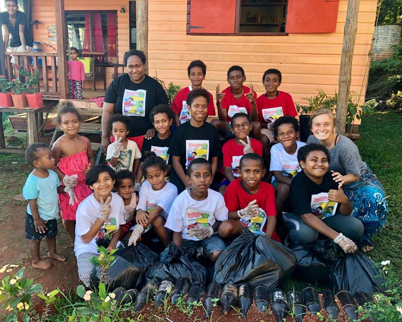 Mariah Watts posing with a group of kids in front of a garden in Fiji.