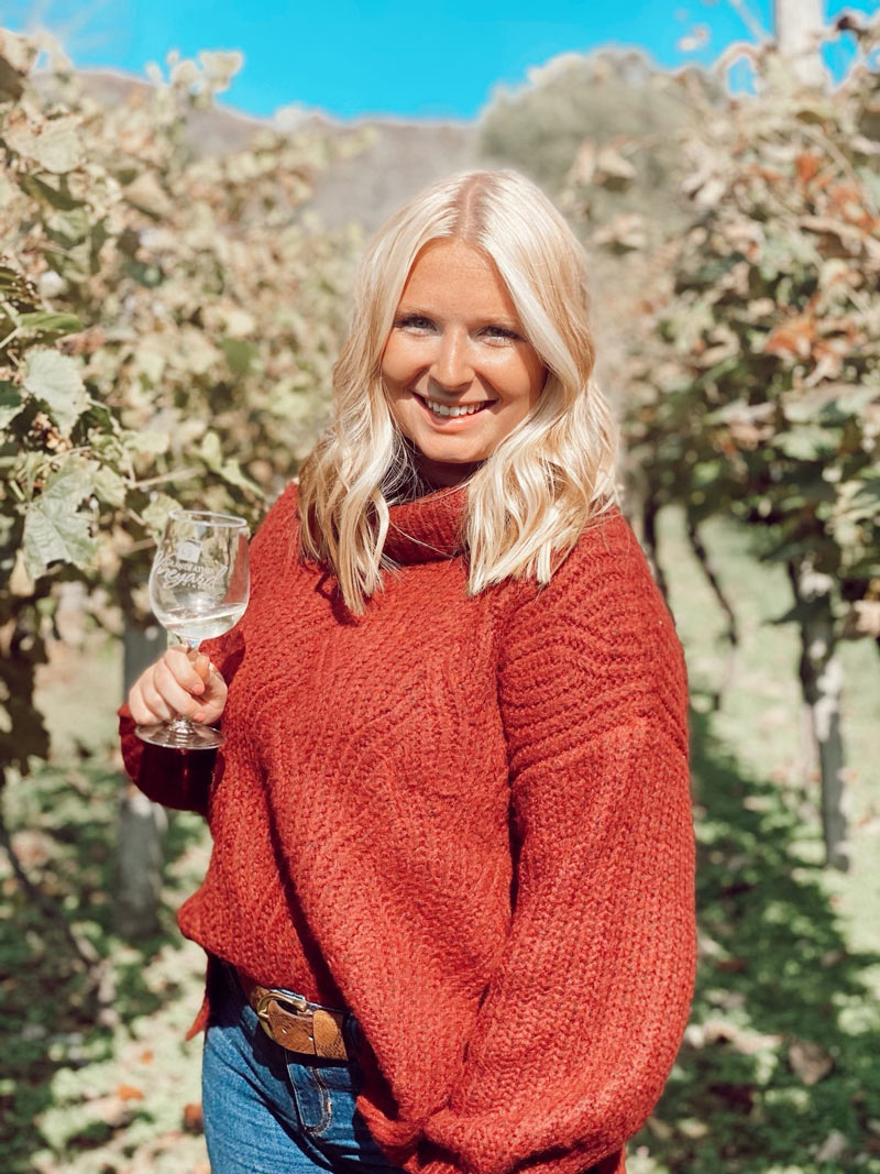 Stephanie Kesselring standing in a vineyard with a wine glass.