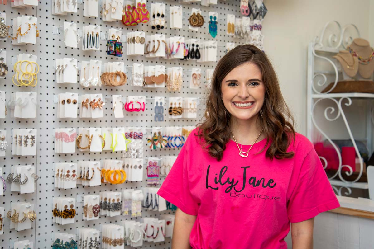 Sarah Jane Levine standing in front of the accessory wall in  here boutique.