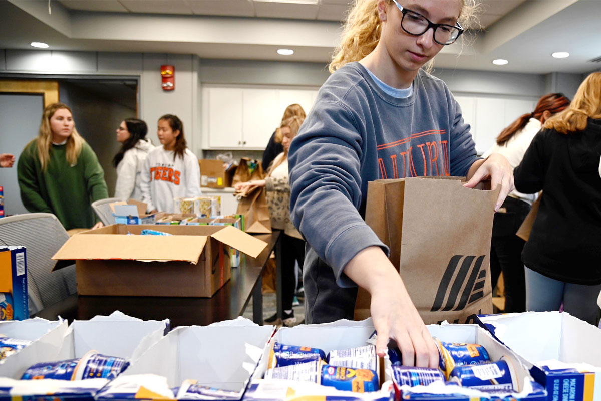 Photo of Auburn Sustenance Project member filling a grocery bag.