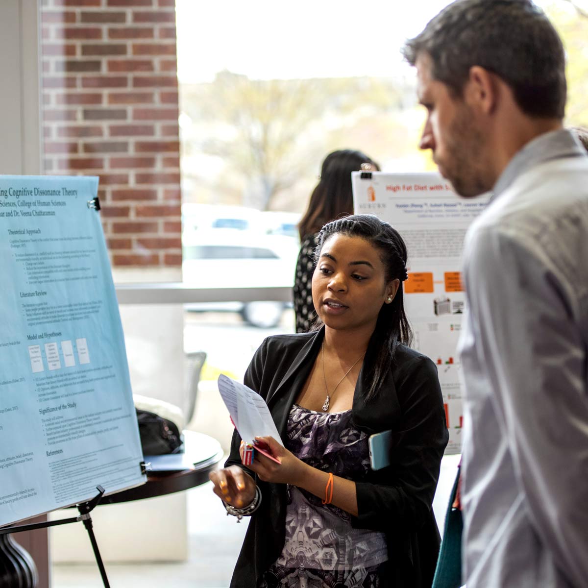 Female student discussing a poster presentation with a male professor.