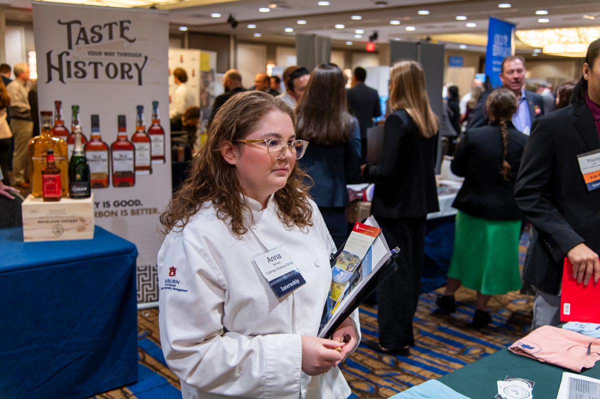 Female student in pink blazer looking at a vendor table.