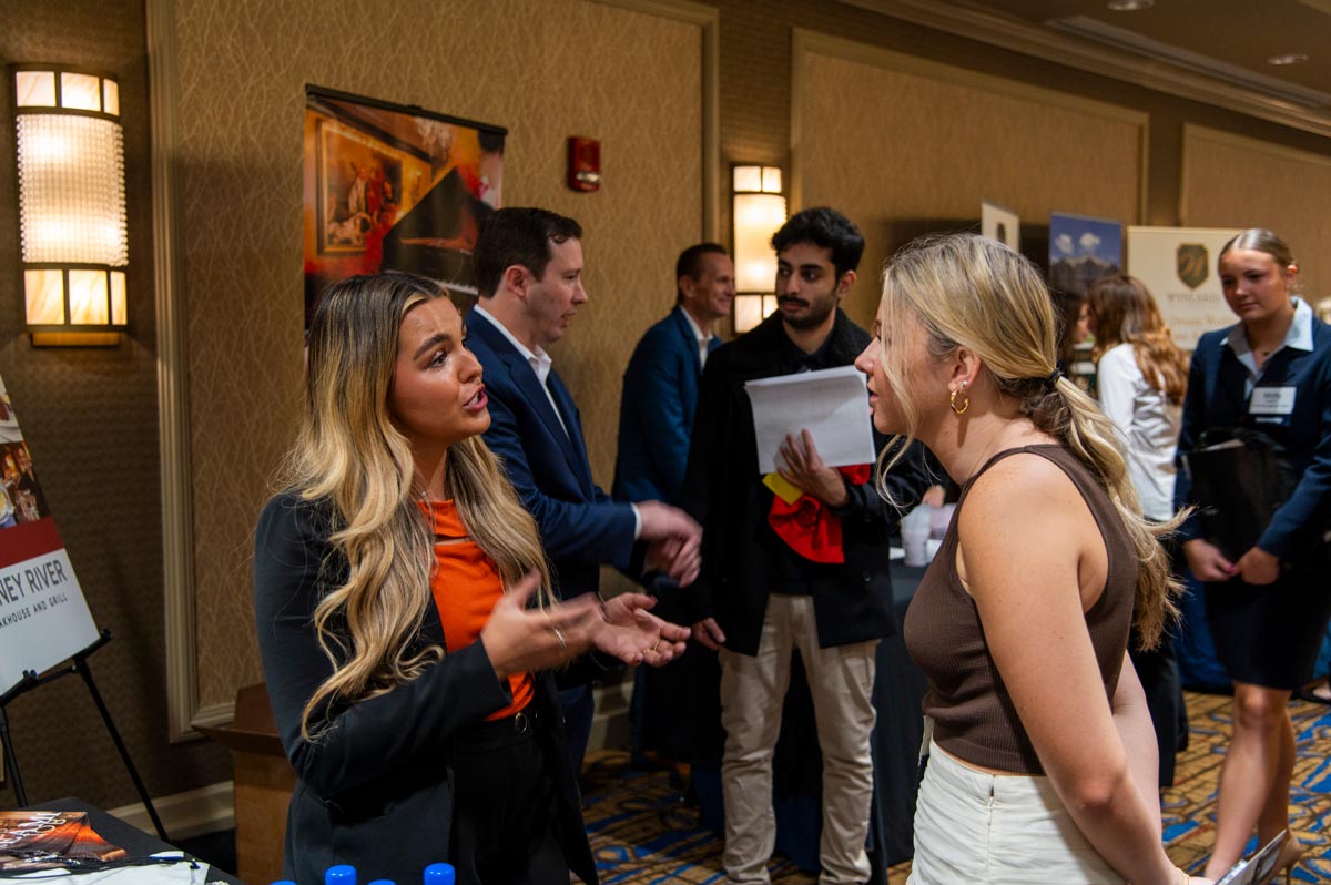 Female student in pink blazer looking at a vendor table.