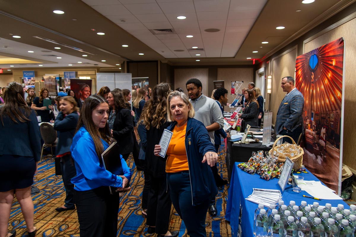 Male student receiving a brouchure from a vendor at the career fair.