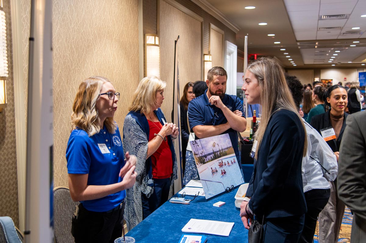 Group of students talking to vendors at hospitality career fair.