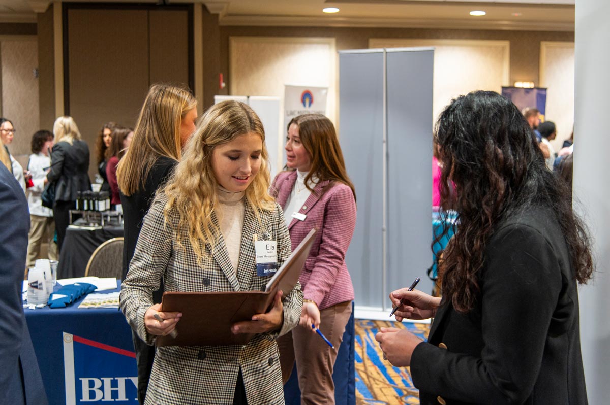 Company representatives standing at their booths at the career fair.