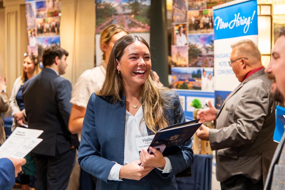 Company representatives standing at their booths at the career fair.