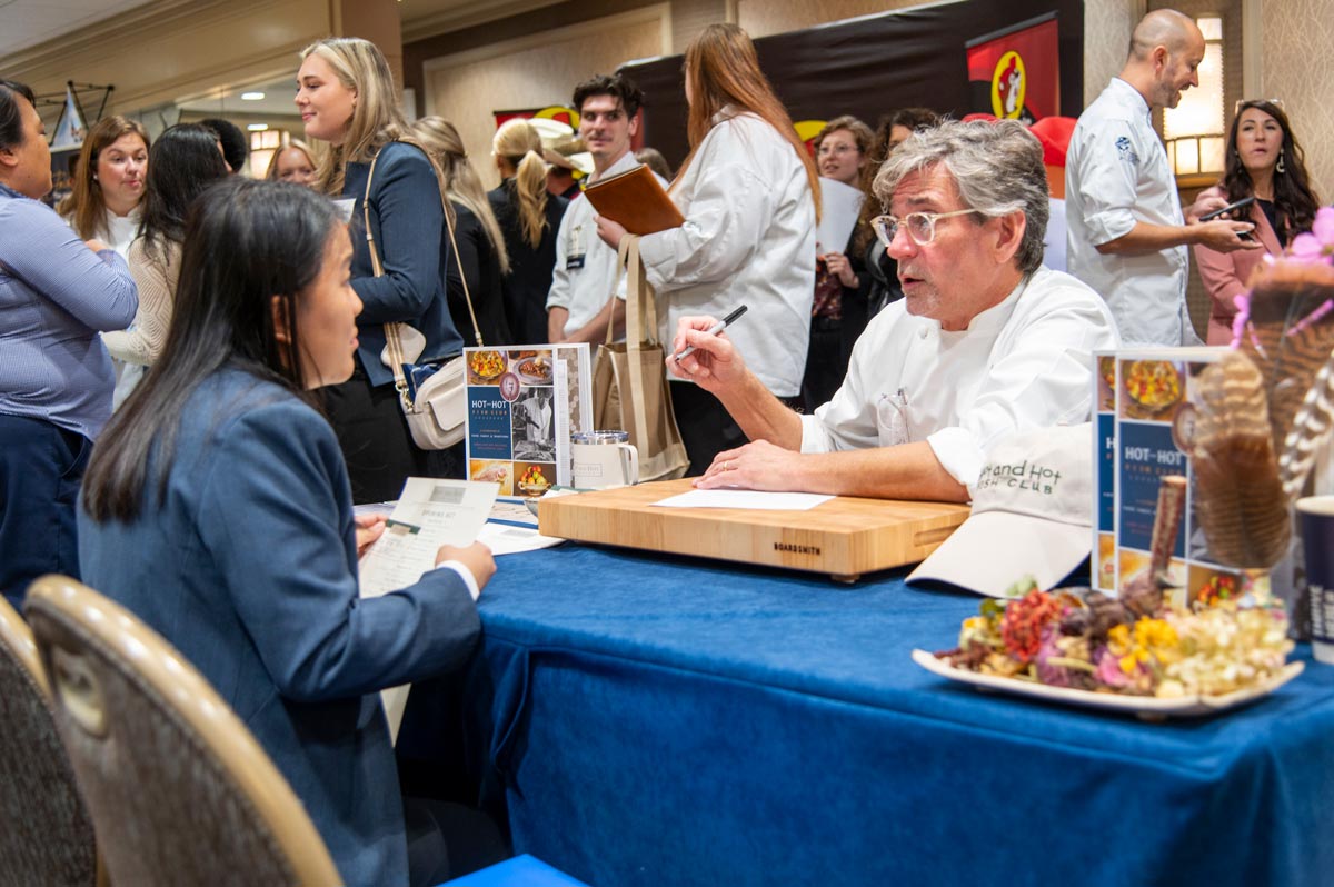 Female student smiling while speaking with one of the vendors at the career fair.