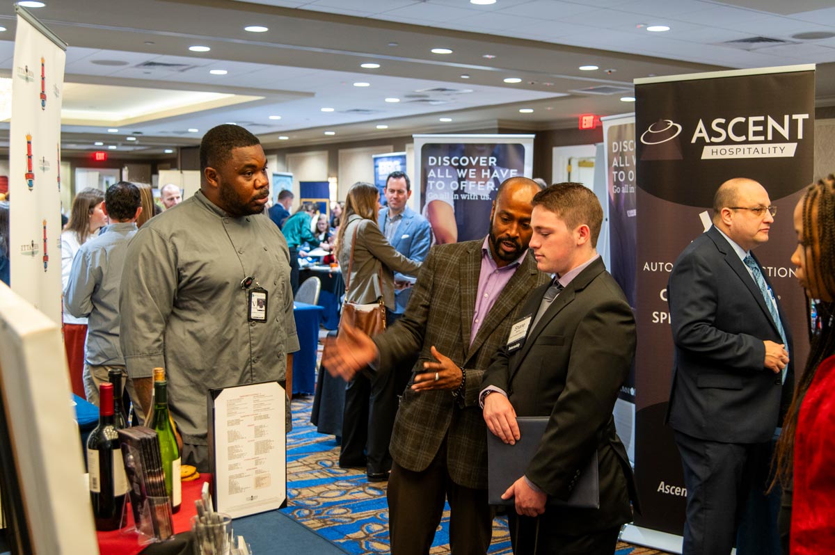 Two female students speaking with a vendor at the career fair. 