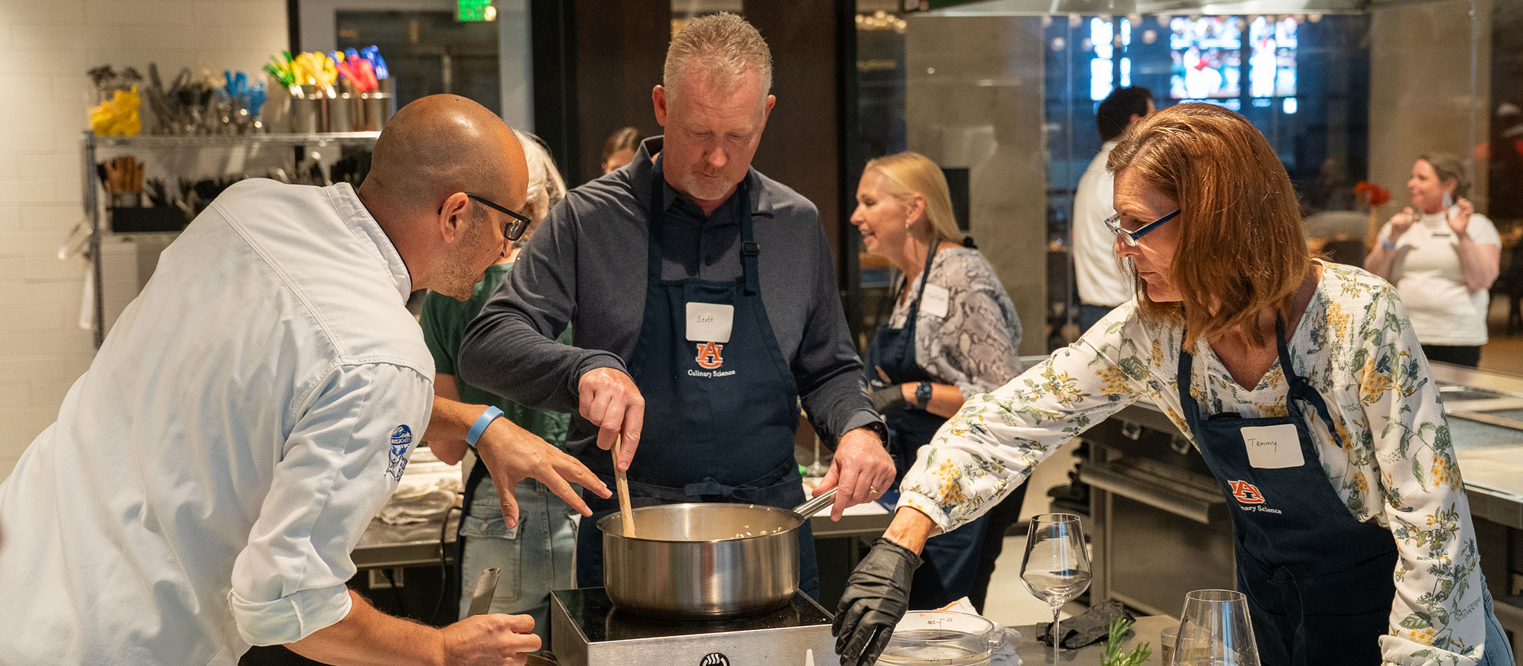 Photo of a man and women learning to cook from chef.