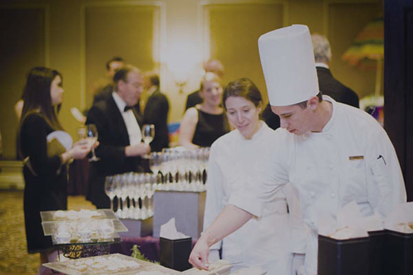 Chef and assistant setting tending a food display.