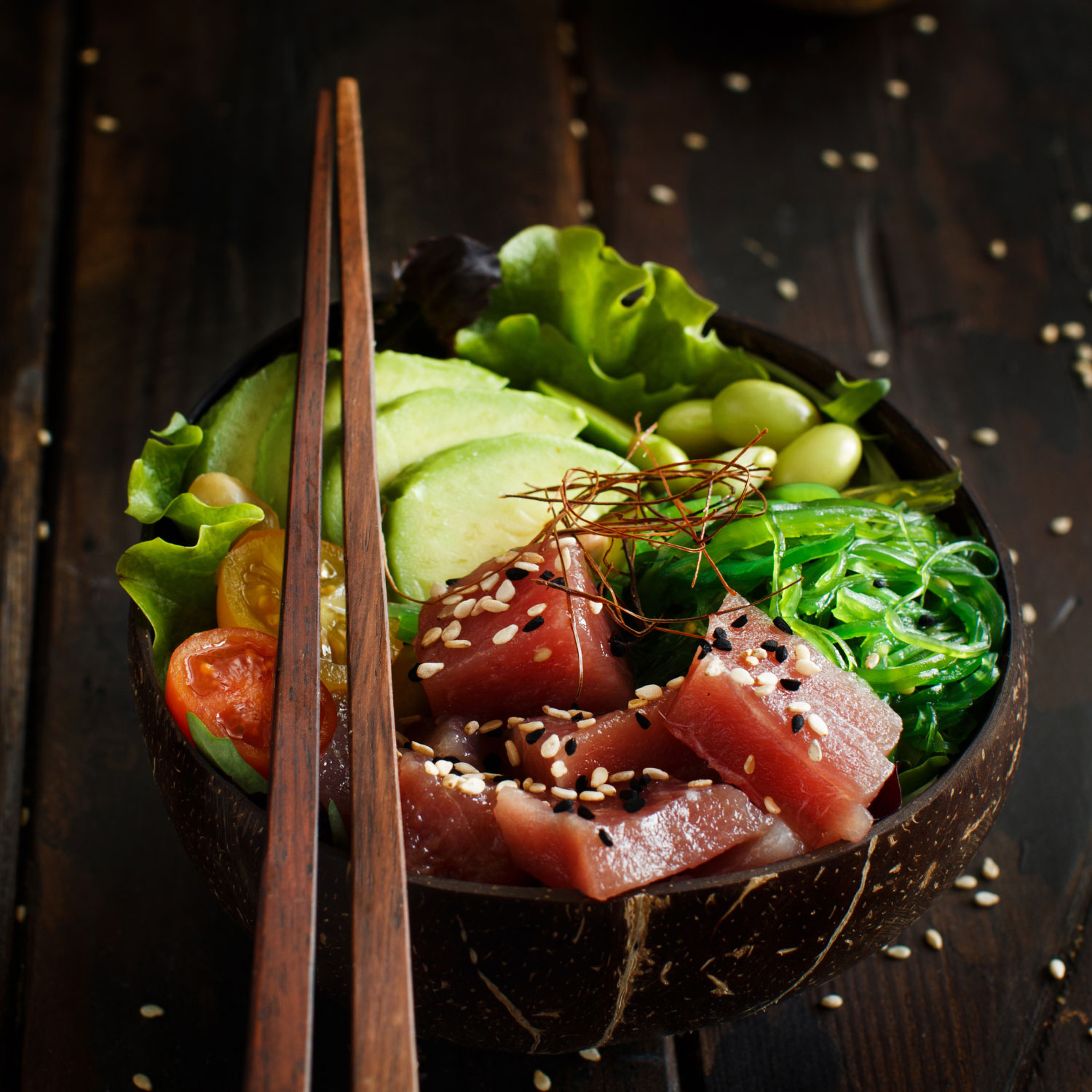 Photo of a bowlwith raw tuna and vegetables and chopsticks.