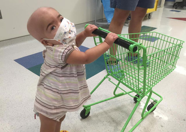 Toddler child pushing a buggy in a hospital.