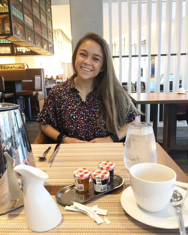 Taylor Blain with a smile on her face sitting at a table.